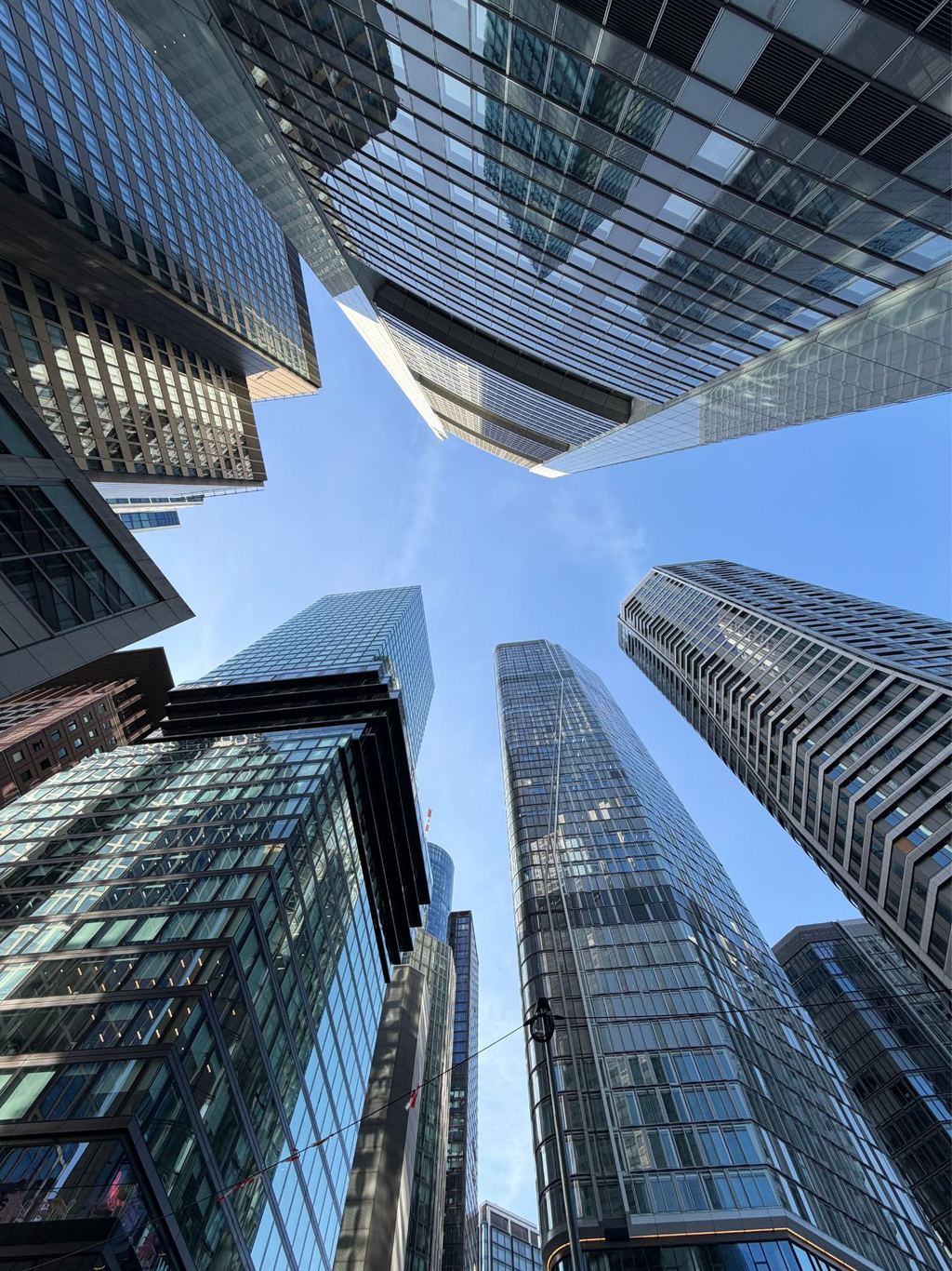Glass office towers rising above a financial district, photographed looking upward